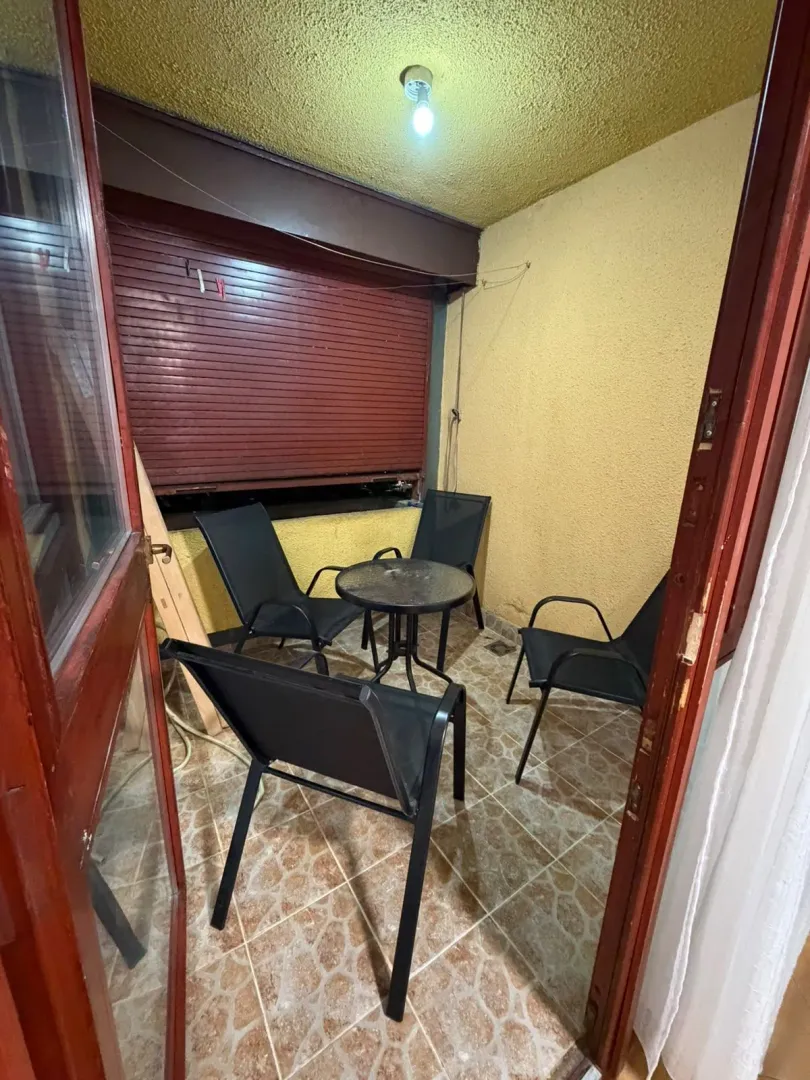 Small covered terrace with a table and four chairs.