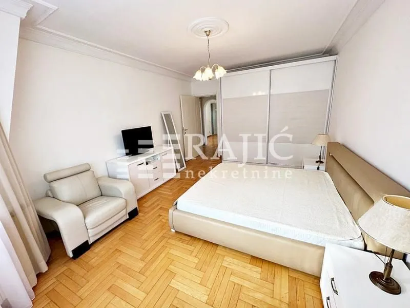 Spacious bedroom with a double bed, wardrobe, and armchair.