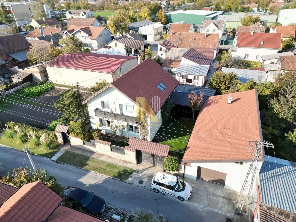 Aerial view of the house with a yard and outbuildings in a neighborhood.