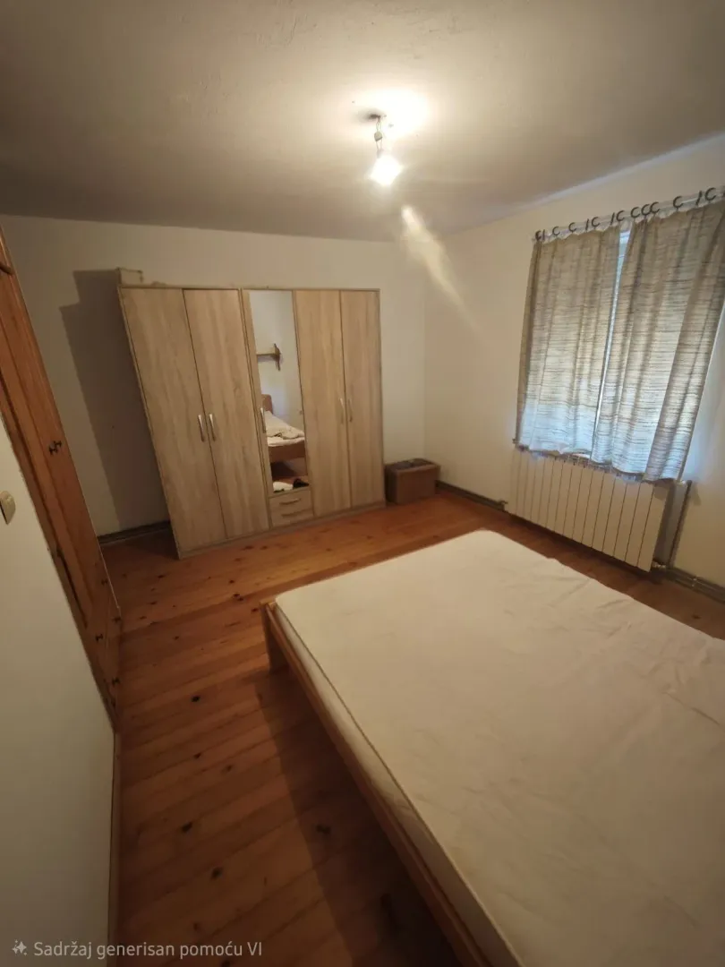 Spavaća soba sa drvenim podom, garderoberom i krevetom.