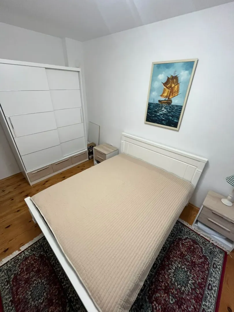 Furnished bedroom with a double bed, wardrobe, and a painting on the wall.