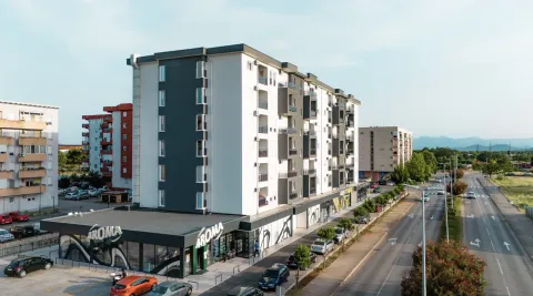 Aerial view of a modern residential and commercial building with surrounding parking and a road. - image 14