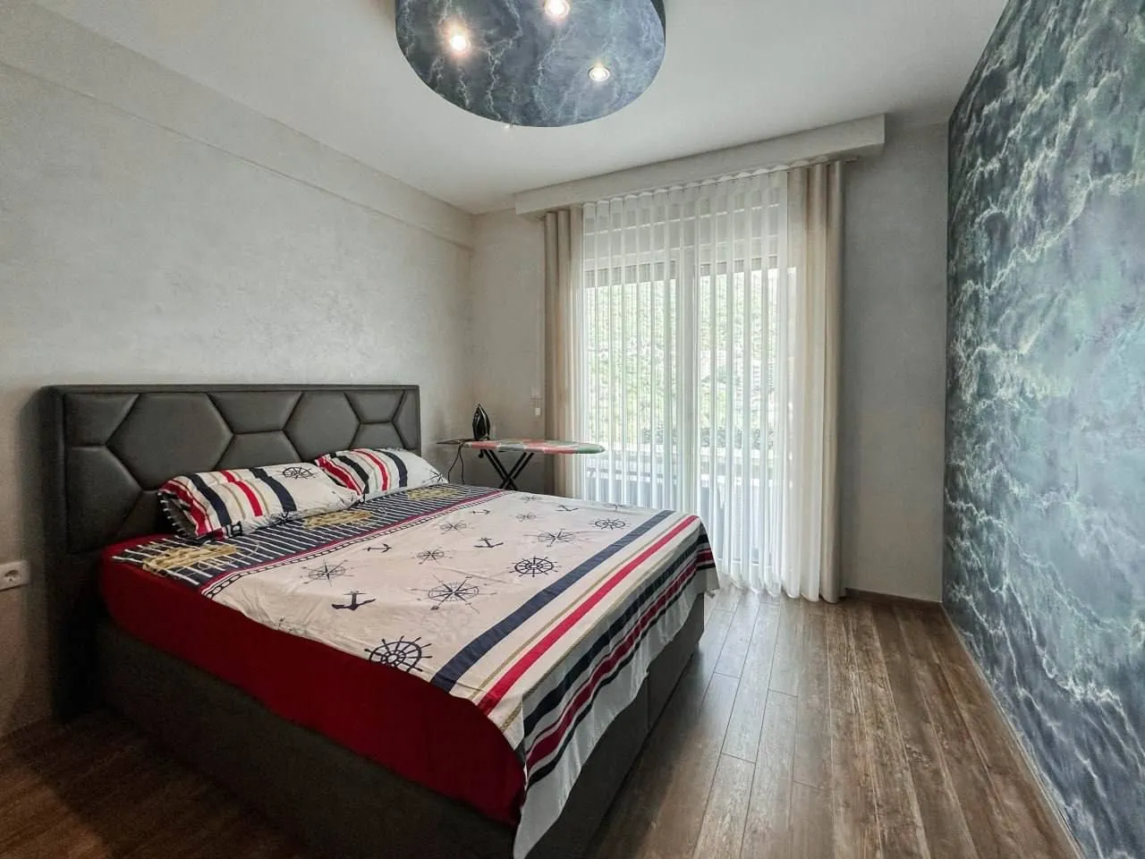 Bedroom with a double bed, decorative wall and access to the terrace.