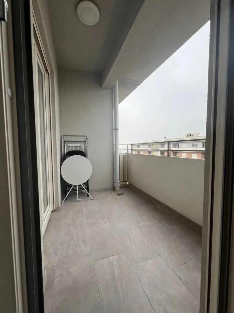 Covered balcony with tiled floor and a view of surrounding buildings.