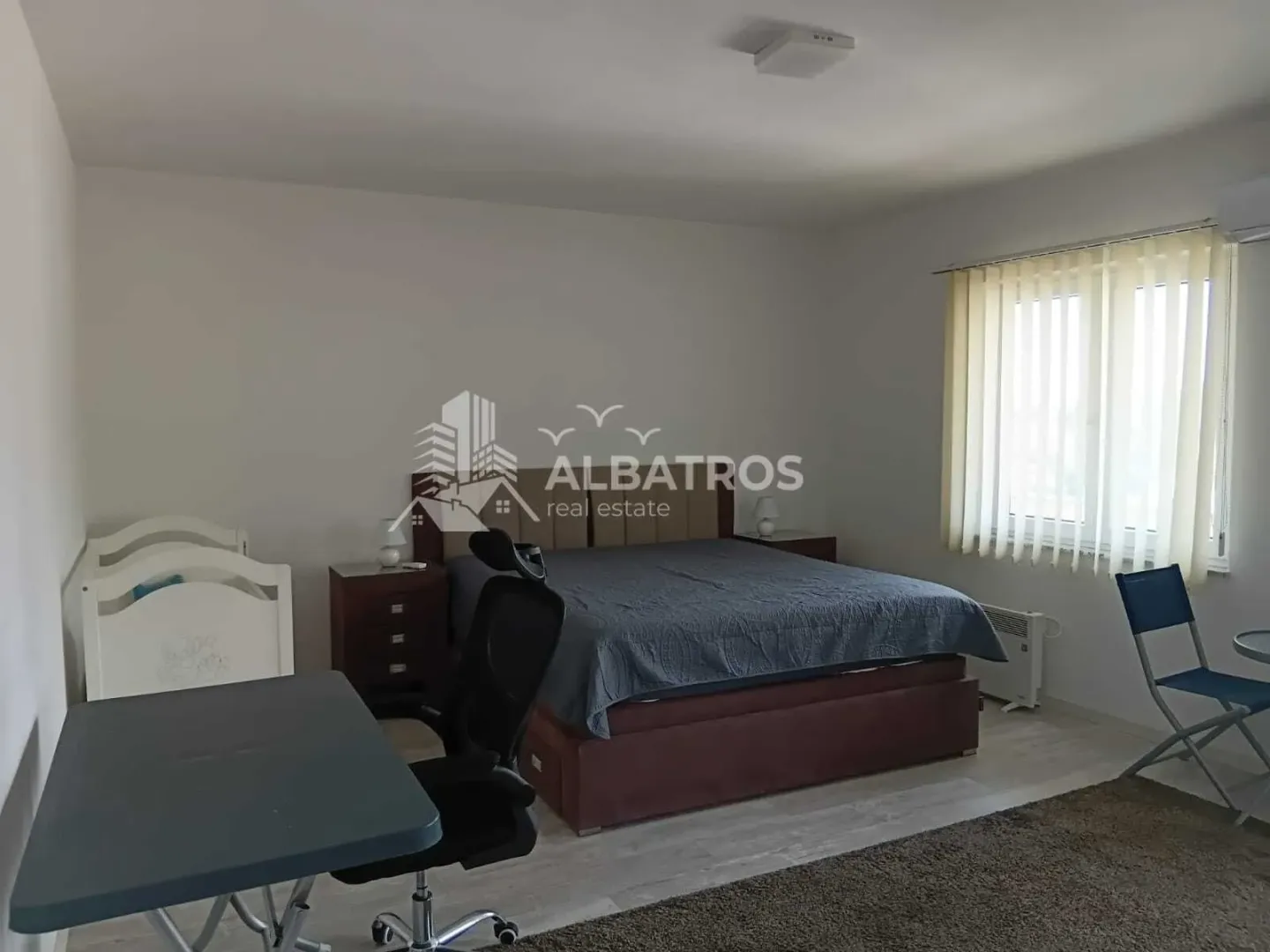 Spacious bedroom with a double bed, desk, and a cot.