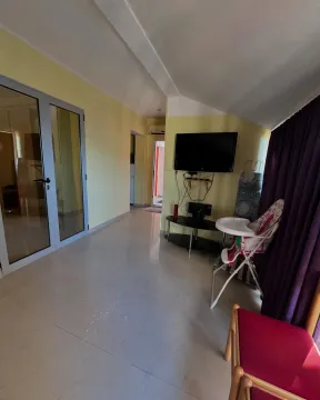 Dnevna soba sa pločicama na podu, televizorom na zidu i tamnim zavjesama. - image 5
