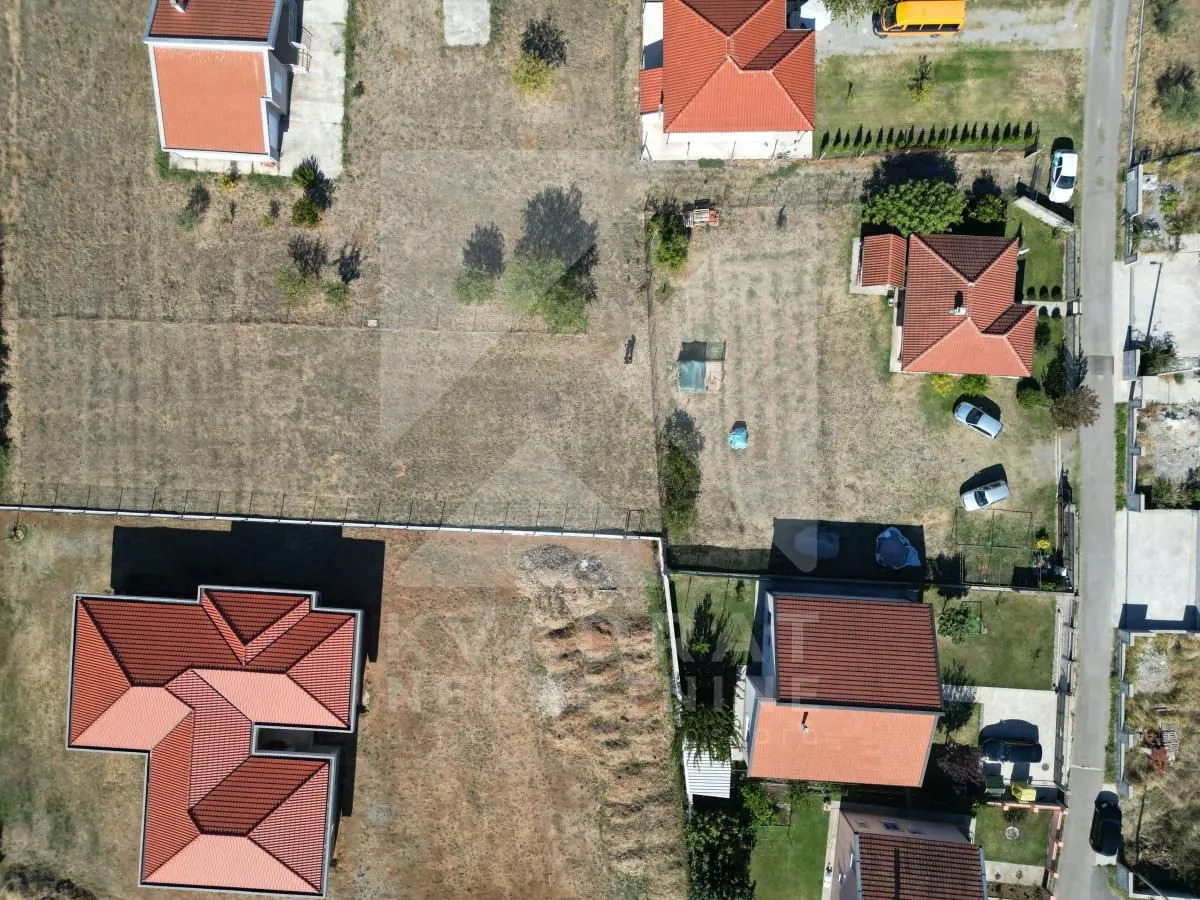 Pogled iz vazduha na kuće sa dvorištima i okolnim zemljištem.