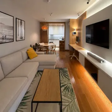 Modern living room with a sofa, TV and desk, connected to the dining area. - image 2