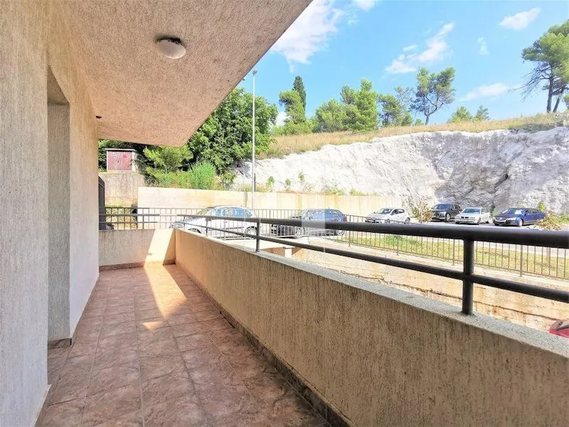 Spacious tiled balcony overlooking the parking area and surrounding greenery.
