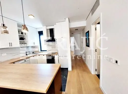 Modern kitchen with white units and a breakfast bar connected to the hallway.