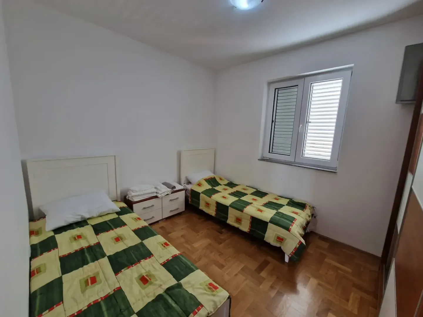 Spavaća soba sa dva singl kreveta i prozorom.