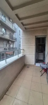 Natkriveni balkon sa popločanim podom i pogledom na susedne zgrade. - image 9