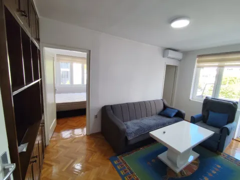 Dnevna soba sa garniturom, stočićem i pogledom na spavaću sobu kroz vrata. - image 2