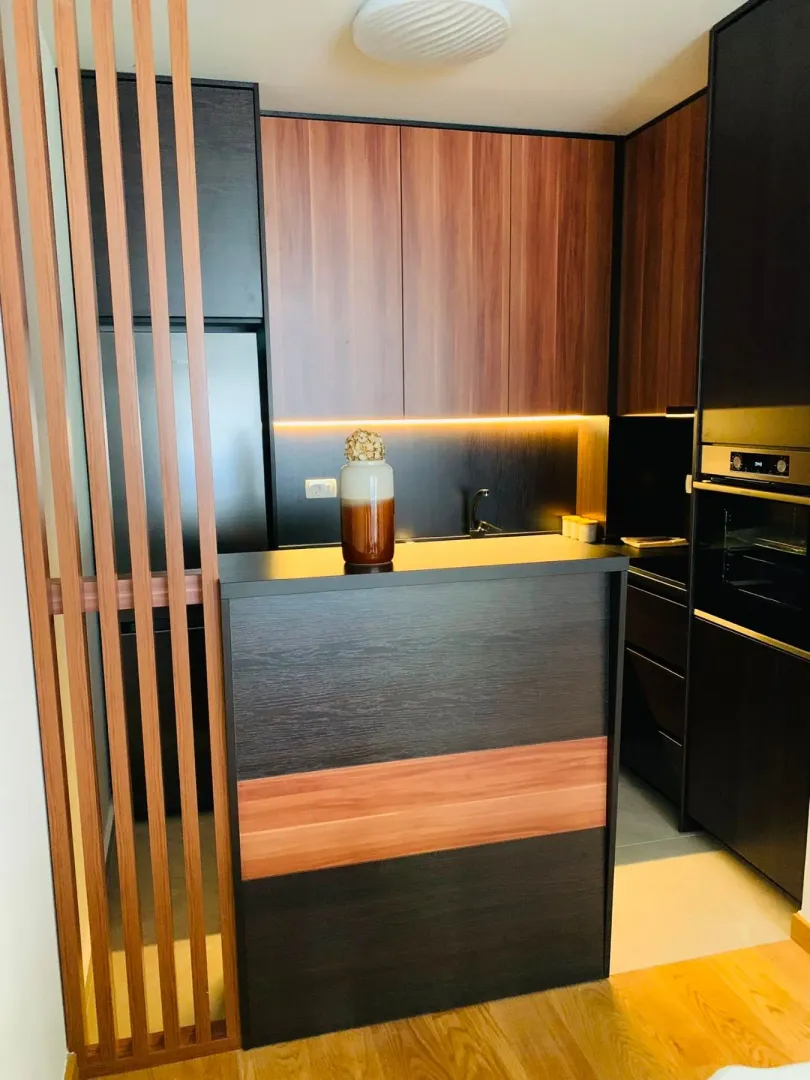 Modern kitchen with dark cabinetry and wooden details.