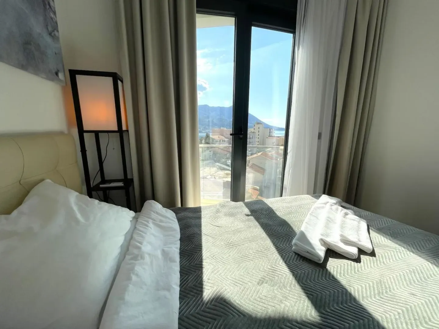 Bedroom with a double bed and a view of the city and sea through the balcony door.