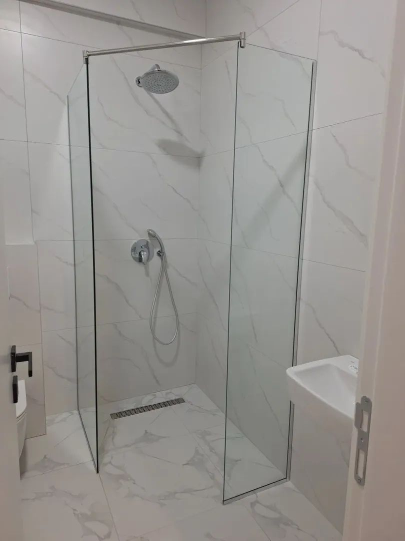 Moderno uređeno kupatilo sa tuš kabinom i umivaonikom.