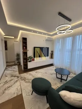 Living room with sofa, TV, and drop ceiling with lighting. - image 3
