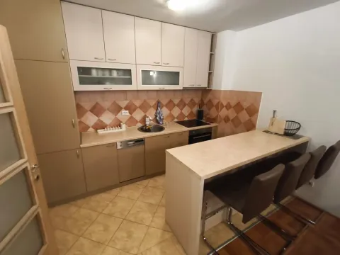 Kitchen equipped with wooden cabinets, featuring a breakfast bar and bar stools. - image 2