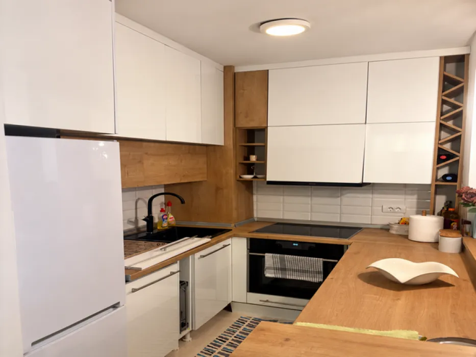 Modern kitchen with white cabinets, wooden countertops, and built-in appliances.