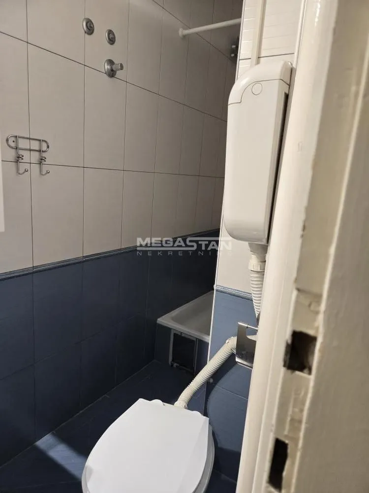 View of the bathroom with a toilet and wall tiles.
