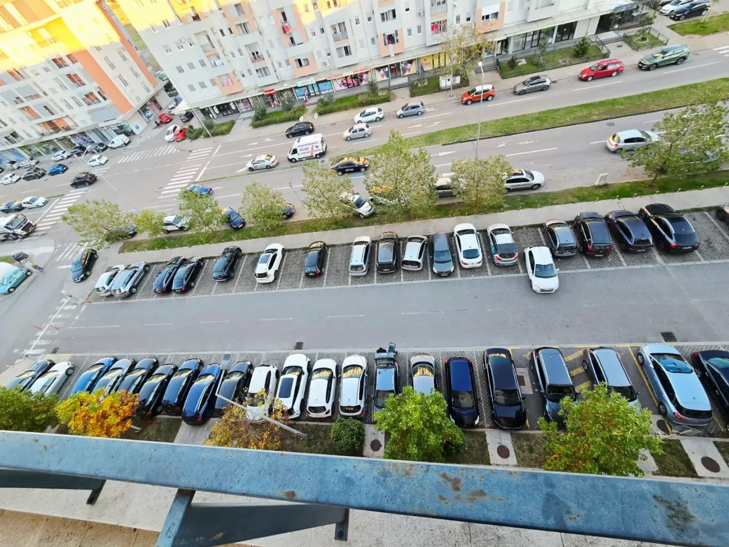 Pogled iz visine na ulicu sa parkingom i okolne stambene zgrade.