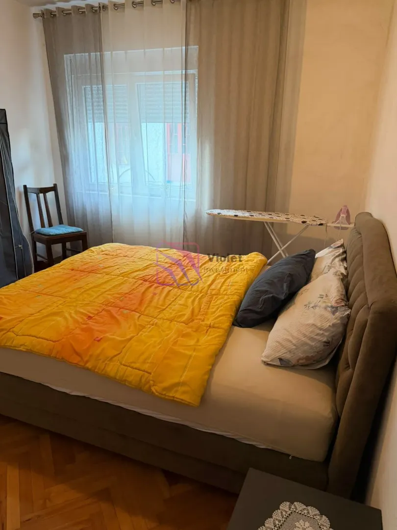 Spavaća soba sa bračnim krevetom i prozorom prekrivenim zavjesama.