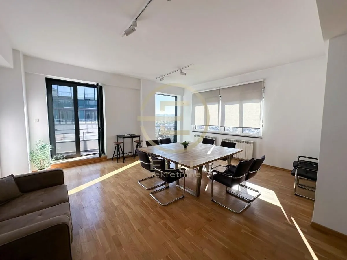 Spacious bright room with a meeting table and a sofa.
