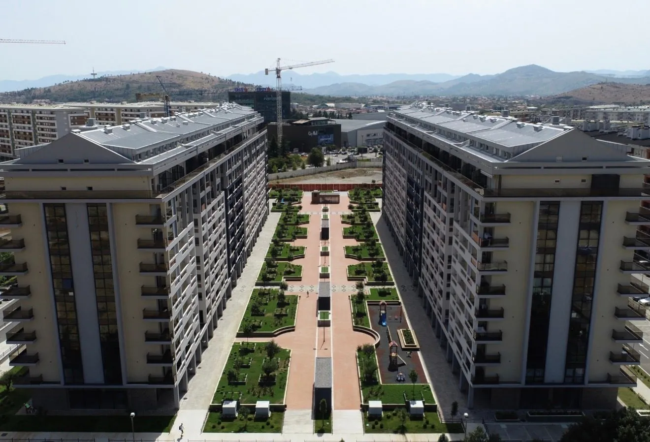 Pogled iz vazduha na stambene zgrade sa uređenim dvorištem i šetalištem između njih.