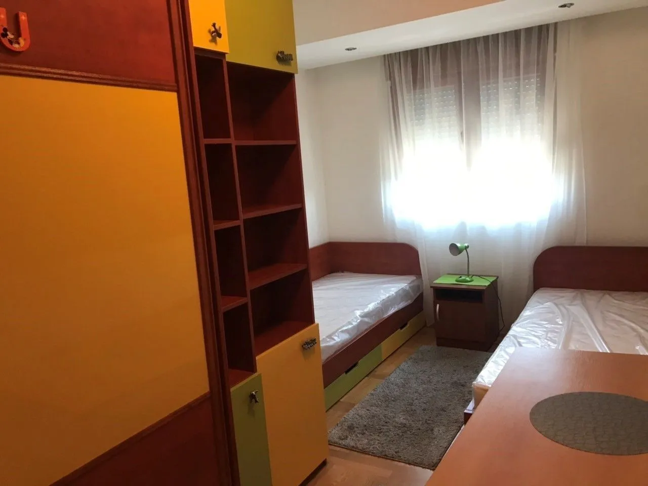 Spavaća soba sa dva kreveta i drvenim ormarom.