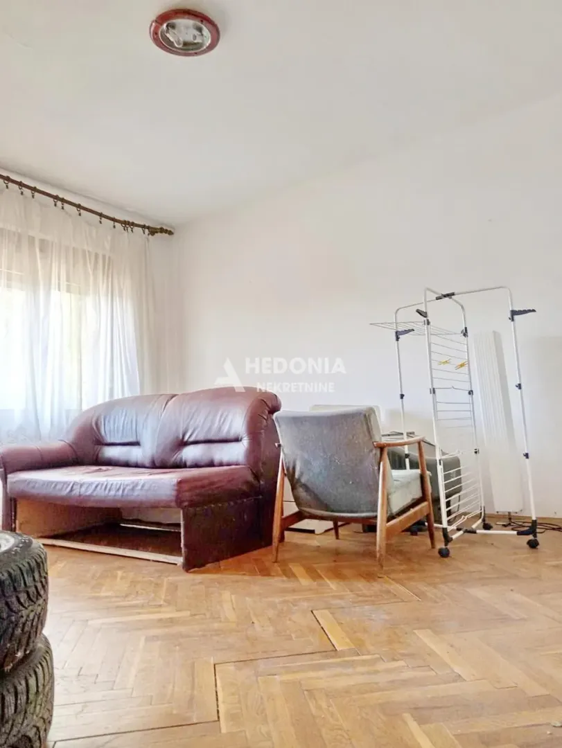 Living room with a sofa, armchair, and parquet flooring.