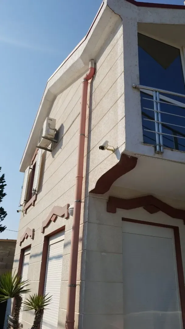Dio fasade dvospratne kuće sa balkonom i roletnama.