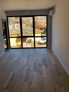 Empty room with wooden flooring and large glass windows. - image 3