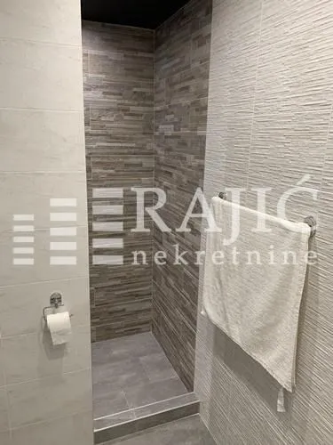 Modernly decorated bathroom with a walk-in shower and stone-look tiles.