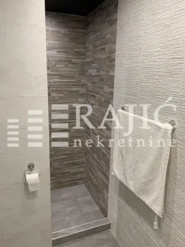 Modernly decorated bathroom with a walk-in shower and stone-look tiles. - image 11