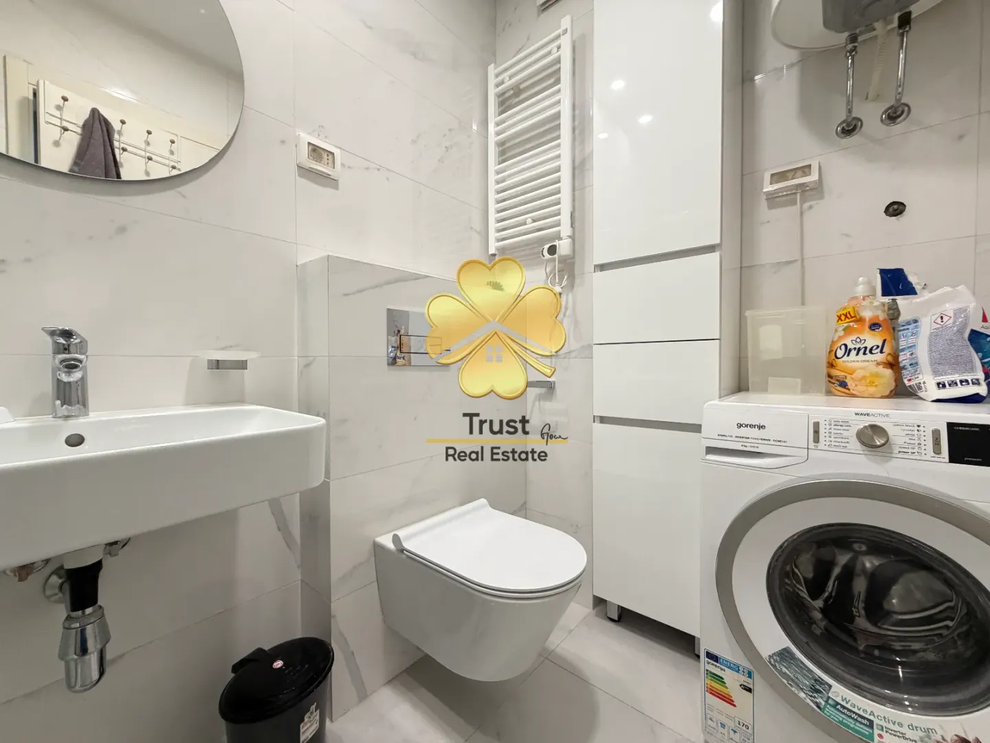 Moderno opremljeno kupatilo sa veš mašinom i sanitetom.