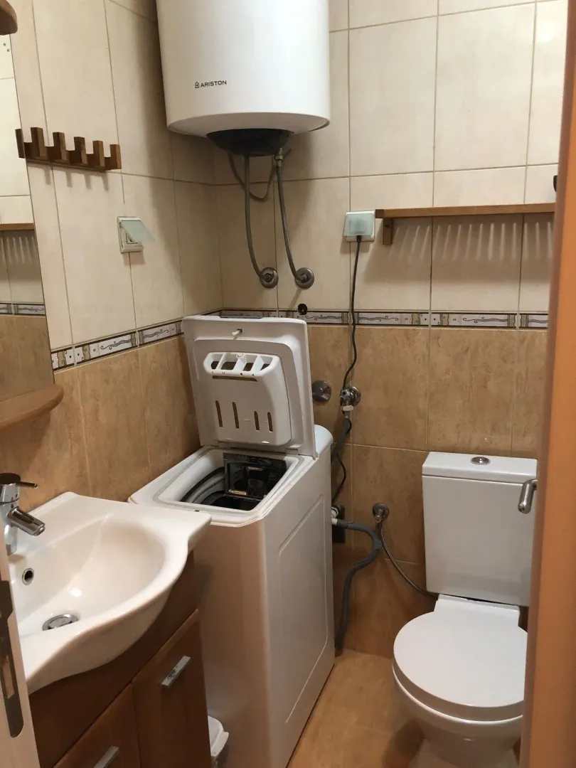 A small bathroom with a washing machine, toilet, and sink.