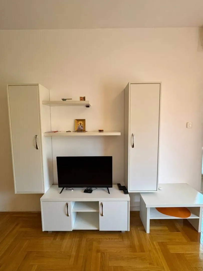 Dnevna soba sa bijelim namještajem i parketom na podu.