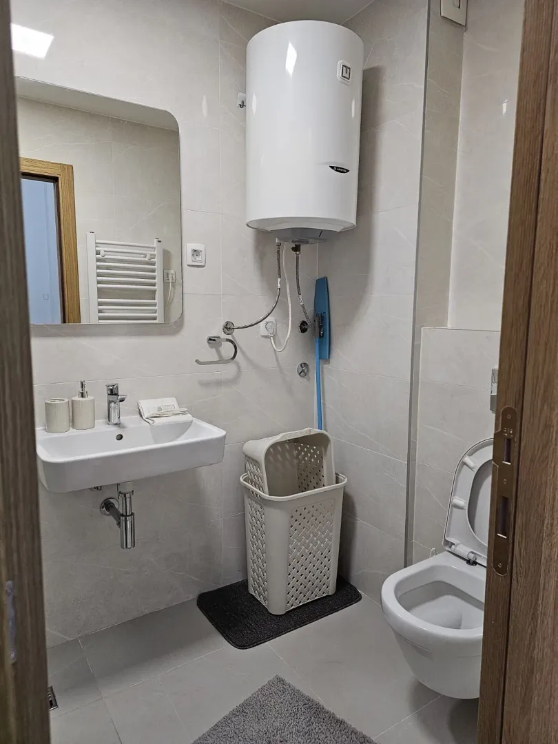 Bright and modern bathroom with a sink, mirror, and water heater.