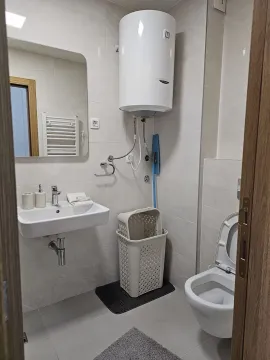 Bright and modern bathroom with a sink, mirror, and water heater. - image 6