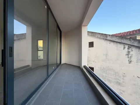 Nenamješten balkon sa sivim podnim pločicama i velikim staklenim kliznim vratima. - image 14