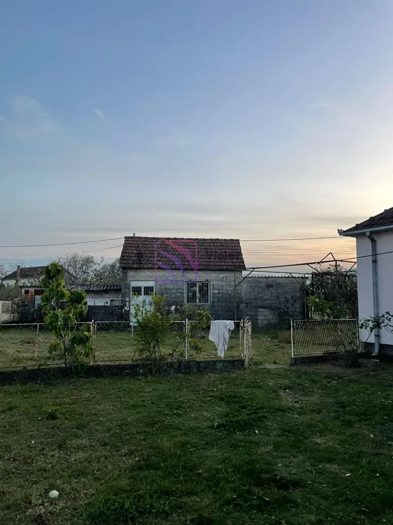 Pogled na dvorište i pomoćni objekat sa travnjakom i ogradom.