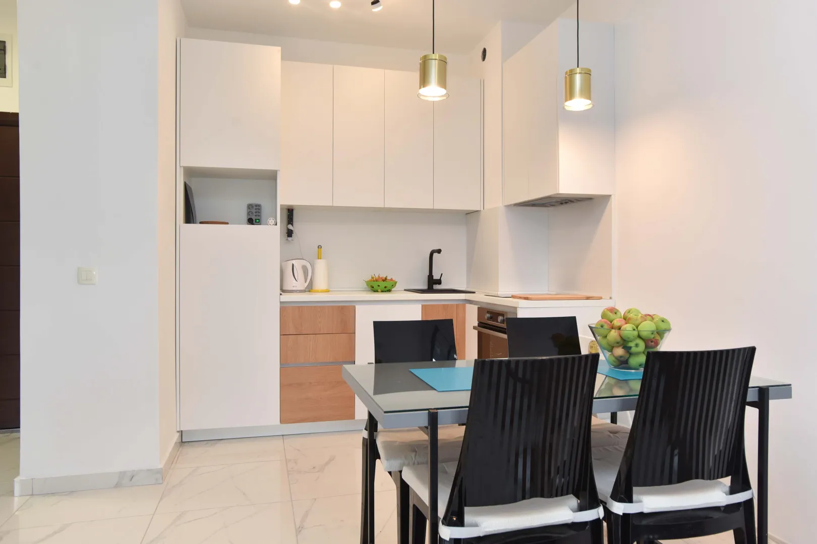 Moderna bijela kuhinja sa trpezarijskim stolom i stolicama.