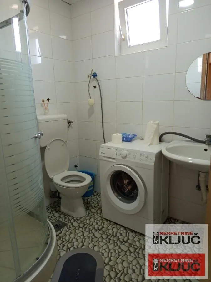 Kupatilo opremljeno tuš kabinom, toaletom, umivaonikom i veš mašinom.