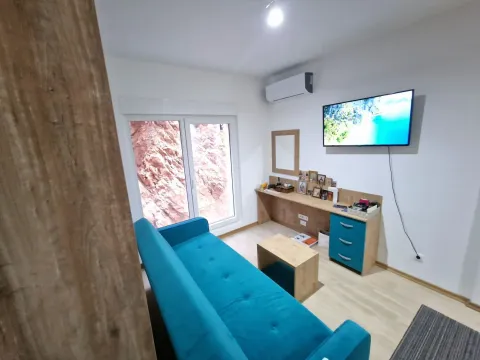 Living room with a blue sofa, wall-mounted television, and a desk. - image 4
