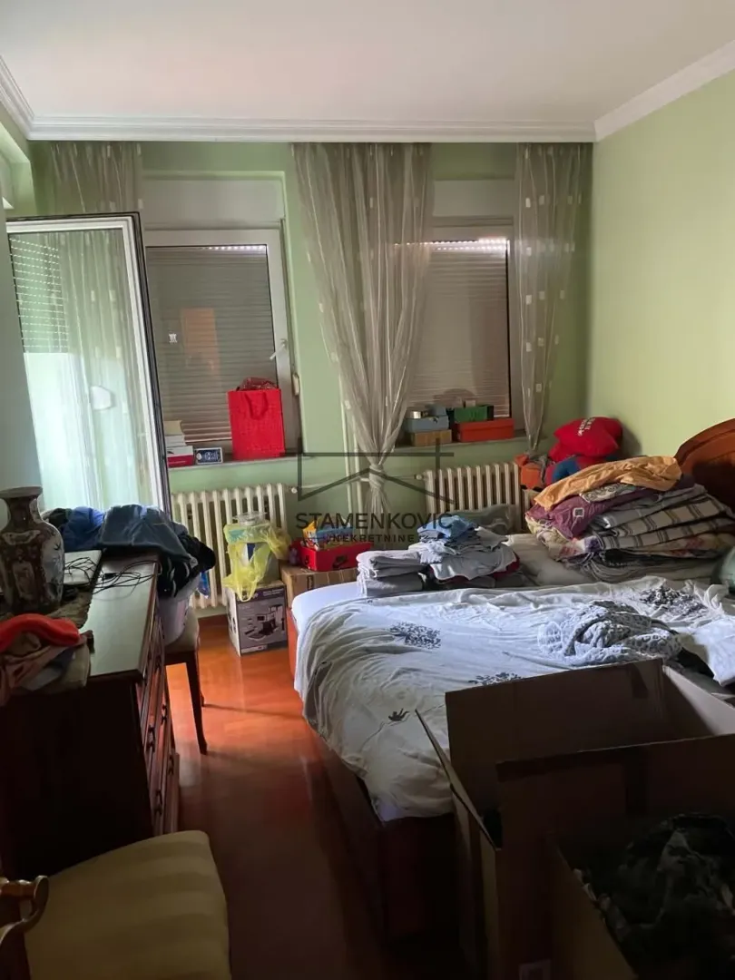 Nameštena spavaća soba sa bračnim krevetom i izlazom na terasu.