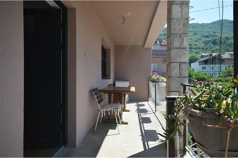 Spacious covered terrace with a table, chairs, and potted flowers.