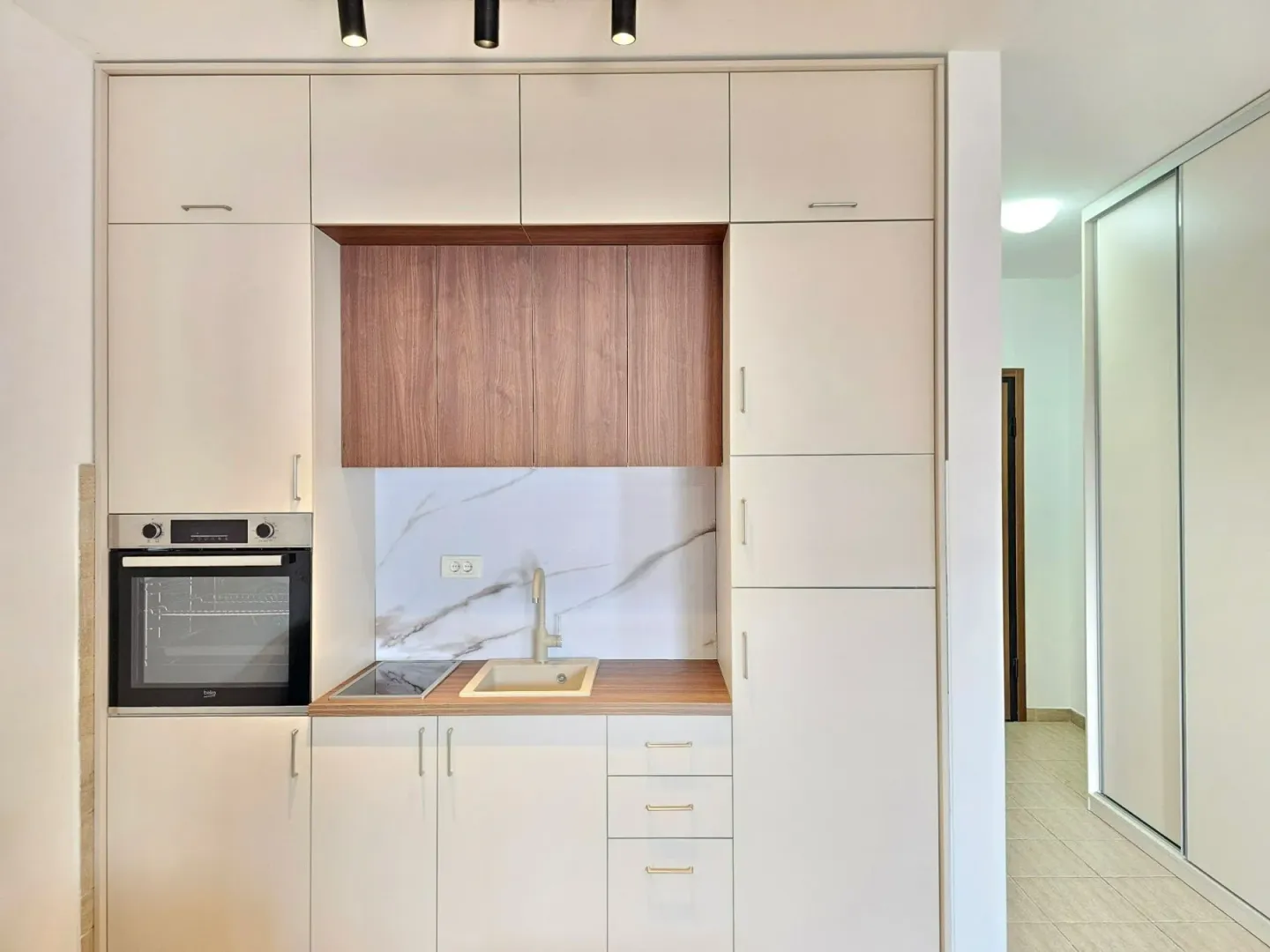 Compact kitchen with built-in cabinetry and appliances.