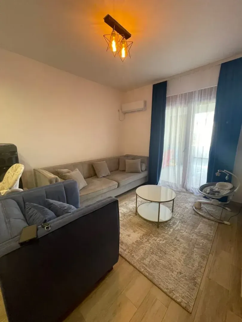 Dnevna soba sa garniturom, stočićem i izlazom na terasu.