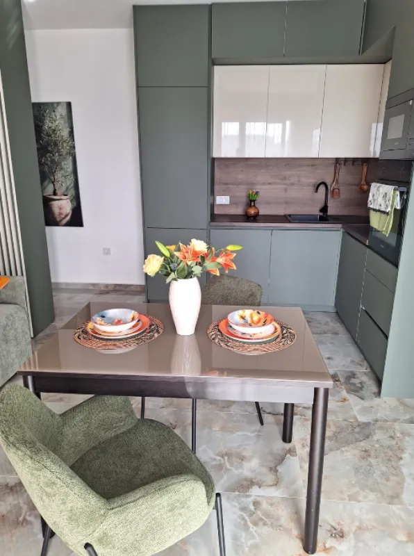Dining table with chairs in front of a modern kitchen.