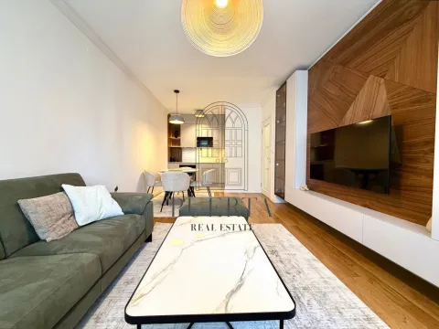 Modern living room with a sofa, TV panel, and dining area in the background. - image 3